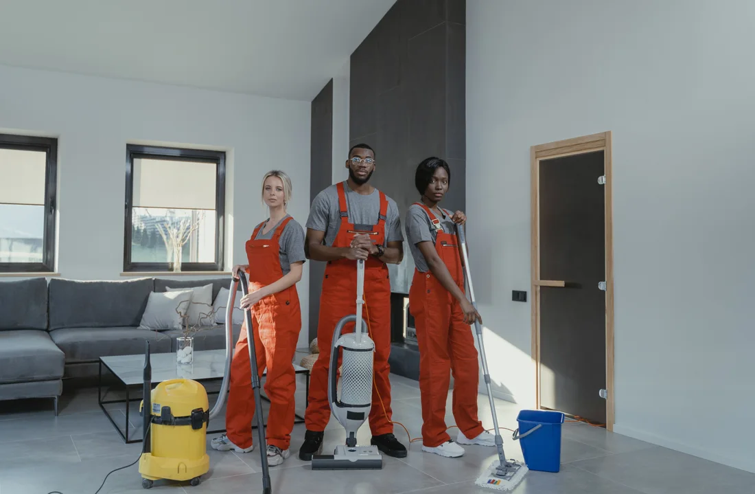 Three cleaning professionals with equipment in a modern home